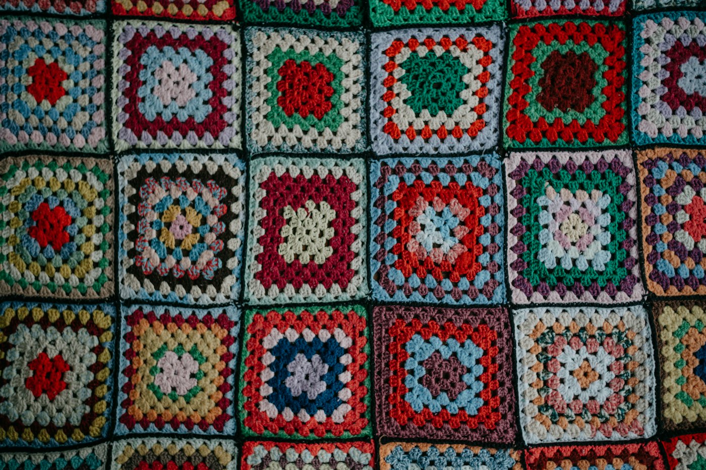 A multicolored granny square blanket with dark borders